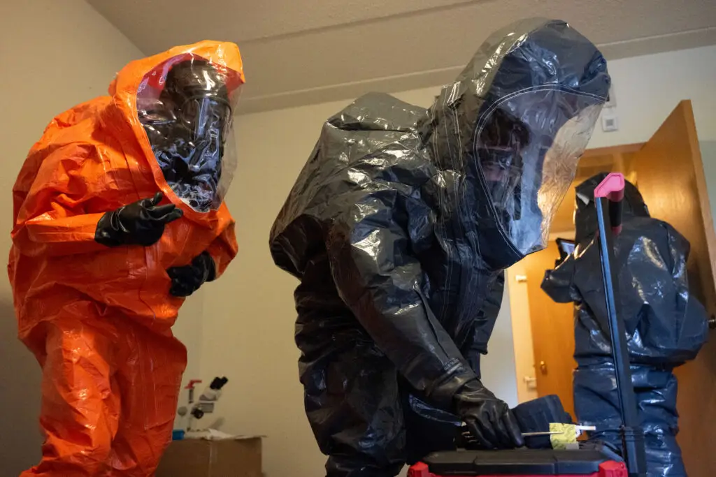 Hazmat responders in Level A fully encapsulated protective suits during emergency response operation, representative scenario for WIS communications integration.